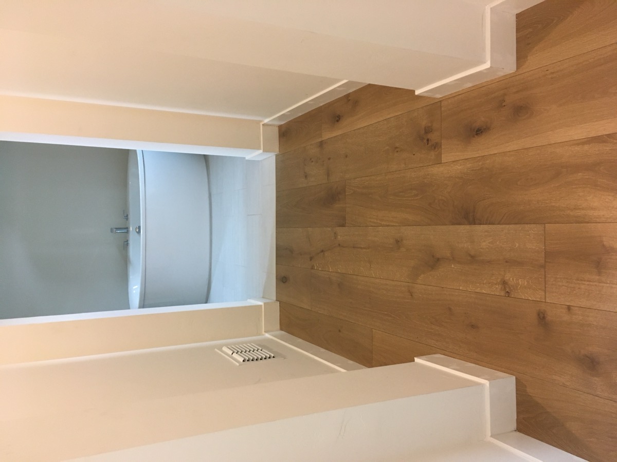 Wide plank white oak hallway leading to a bathroom